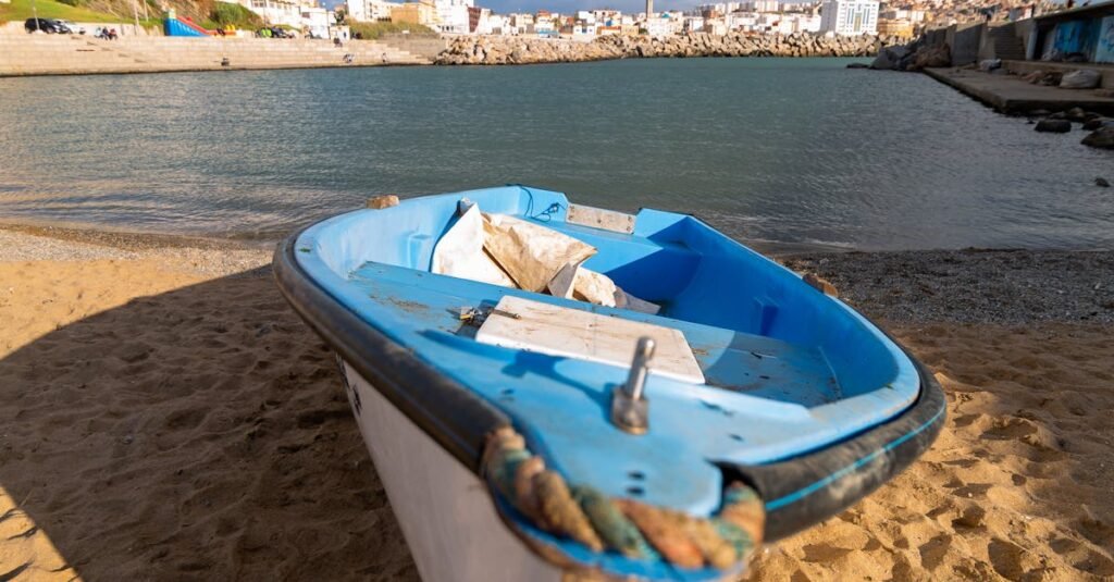 Image actuelle : Small boat on sandy beach with cityscape in Algiers, Algeria in the background.